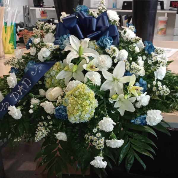 Large white and blue floral funeral spray with lilies and hydrangeas
