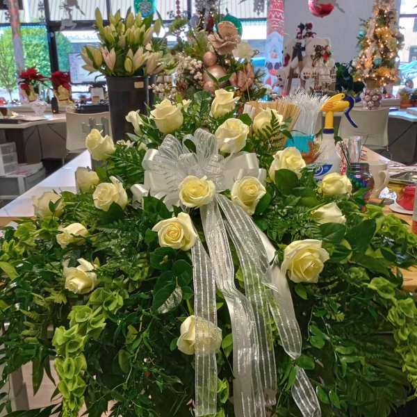 Large white rose arrangement with a silver ribbon and cascading greenery