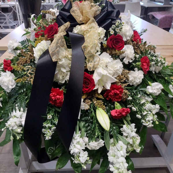 Large funeral spray with red and white flowers and black ribbon