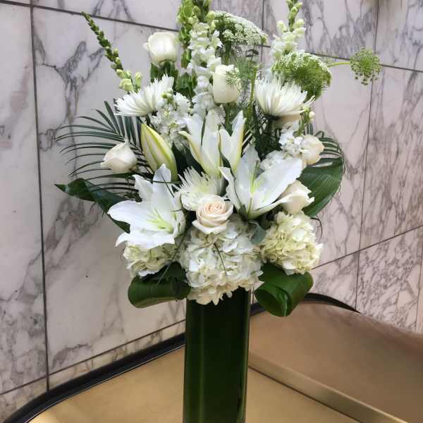 White floral arrangement in a tall green vase