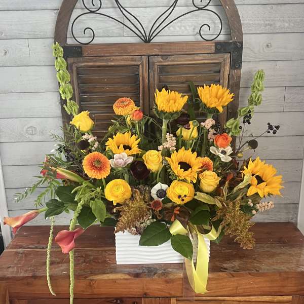 Mixed bouquet in a white rectangular vase with yellow and orange flowers