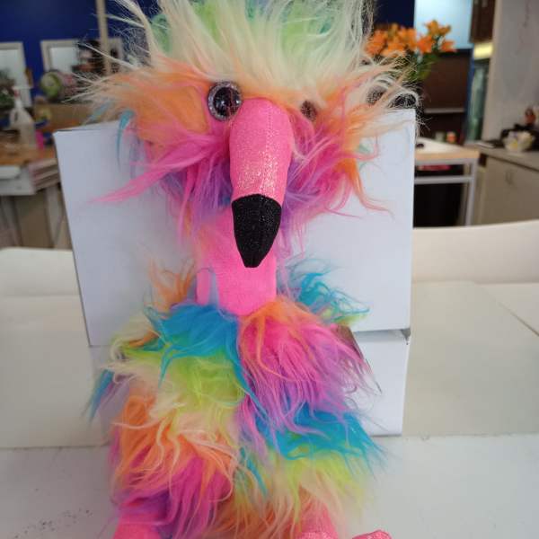 Rainbow plush bird toy with fuzzy multicolor fur and glittery pink beak and feet