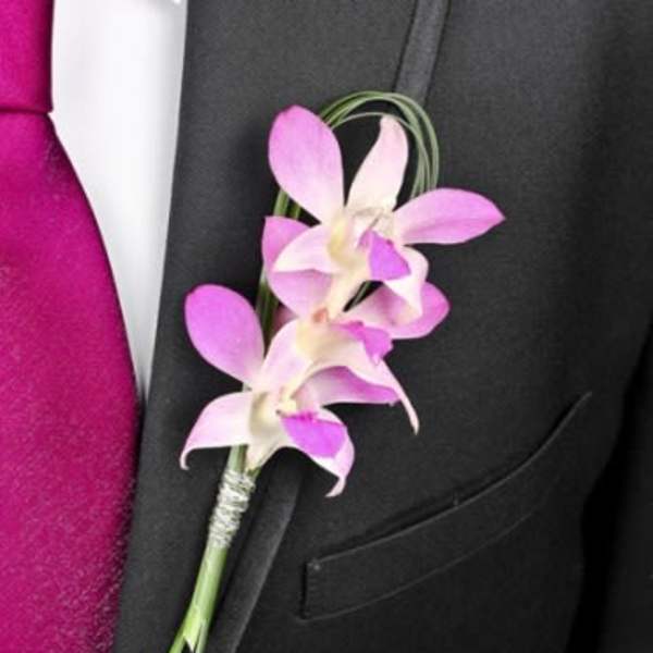 Pink orchid boutonniere pinned to a black suit jacket