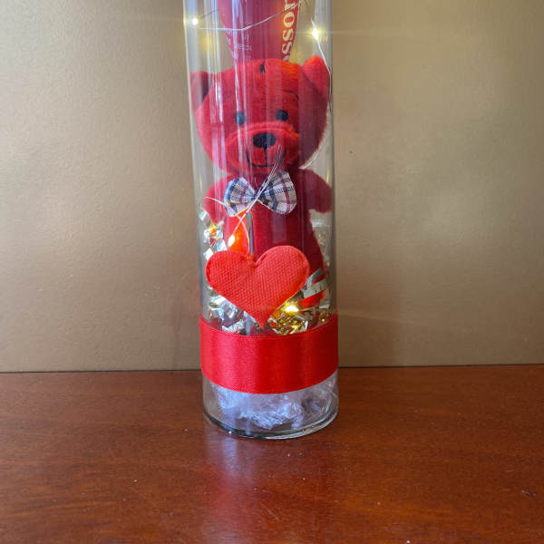 Red teddy bear in a clear tube with a heart and ribbon