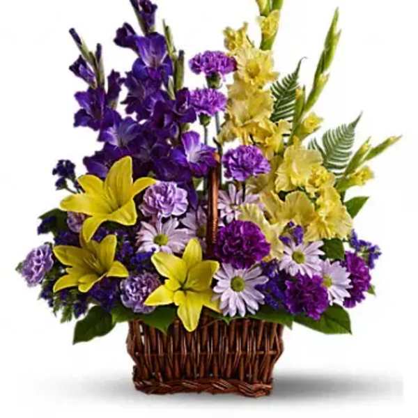 Purple and yellow mixed flower arrangement in a wicker basket