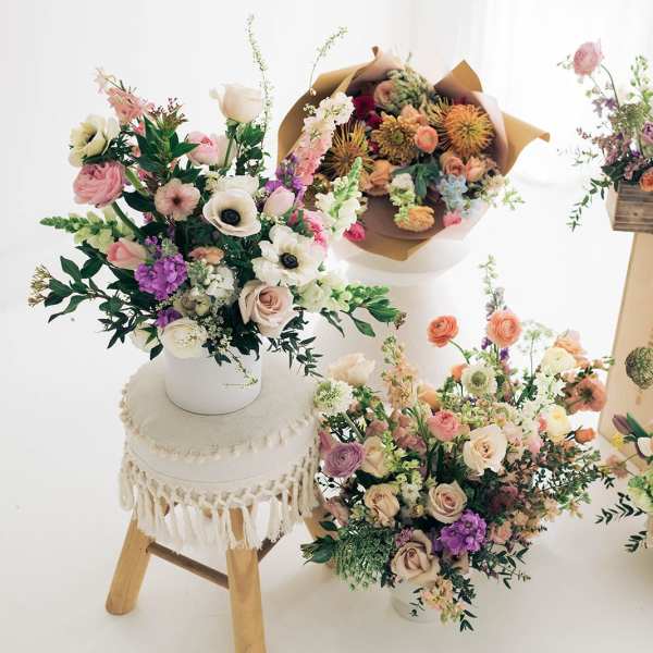Assorted pastel flower arrangements in vases and boxes