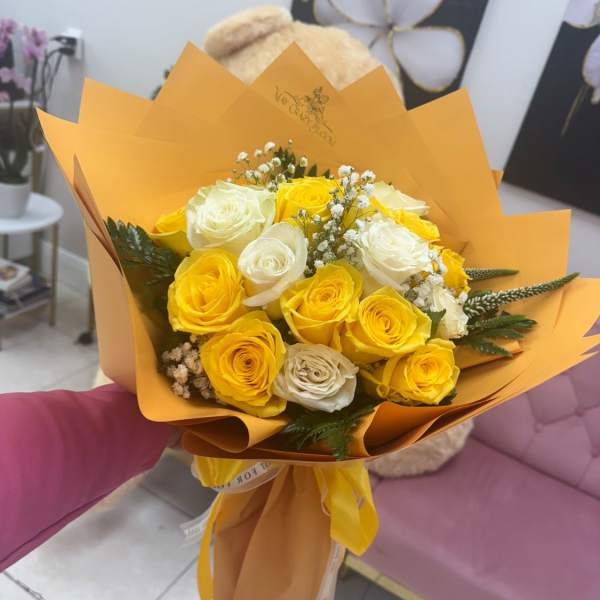 Bouquet of yellow and white roses wrapped in orange paper