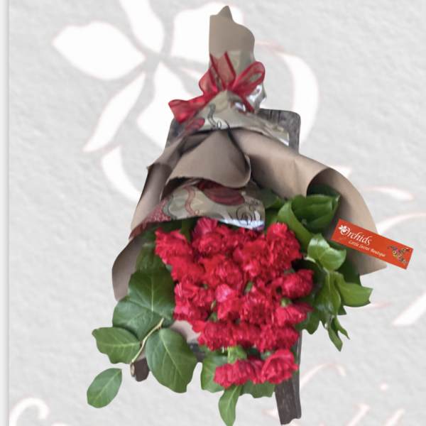 Bouquet of red carnations wrapped in paper with a ribbon