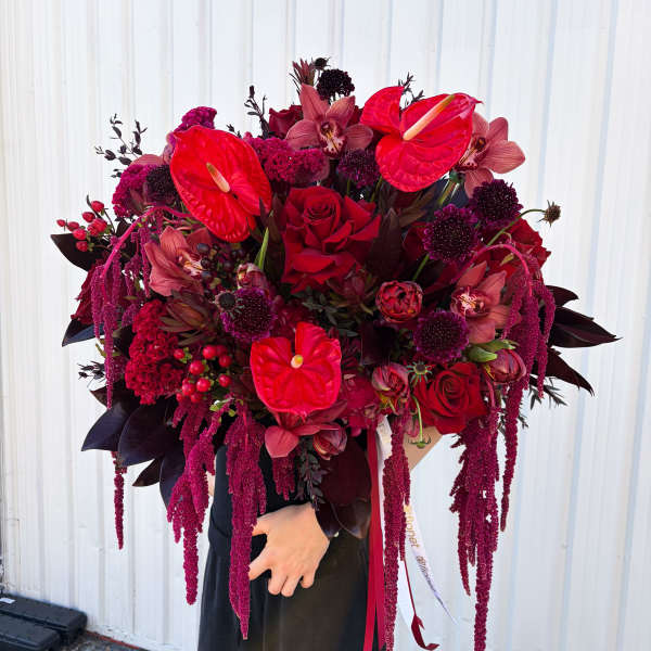 Large bouquet of red roses, anthuriums, and orchids with trailing burgundy accents