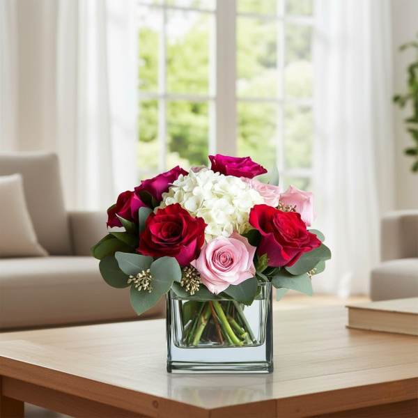Bouquet of red and pink roses with white hydrangea in a glass vase