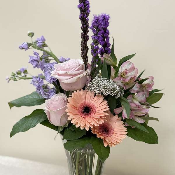 Mixed bouquet of pink and purple flowers in a clear glass vase
