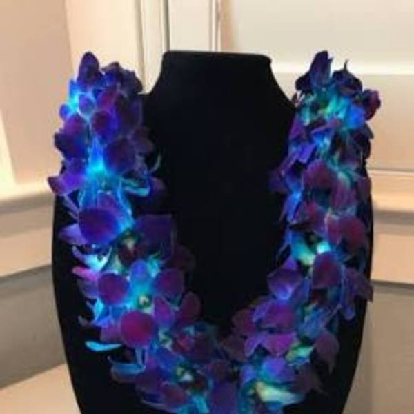 Purple orchid lei draped over a black bust display
