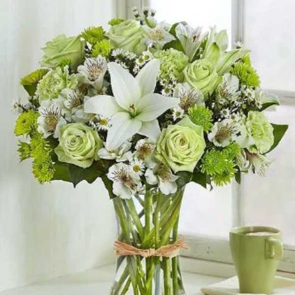 Green and white bouquet with lilies and roses in a glass vase