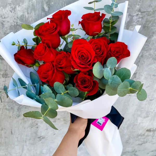 Bouquet of red roses wrapped in white paper with eucalyptus