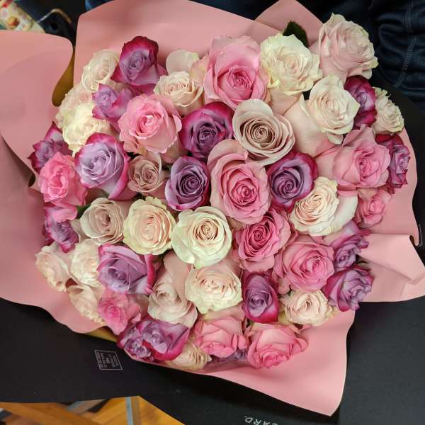 Large bouquet of pink, white, and lavender roses wrapped in pink paper