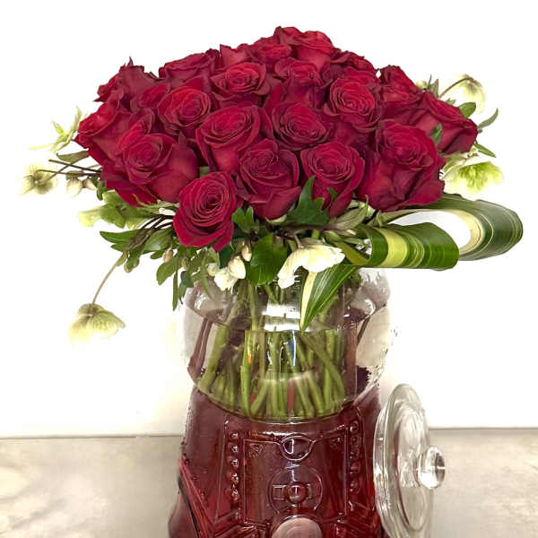 Red rose bouquet in a clear glass vase with a red base
