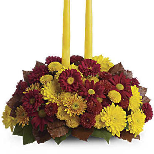 Yellow taper candles in a low arrangement of red and yellow mums