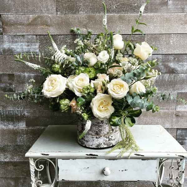 White rose arrangement in a rustic metal container