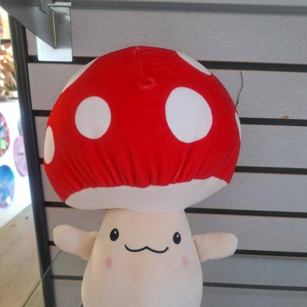 Plush mushroom toy with a red polka-dot cap and smiling face displayed on a shelf