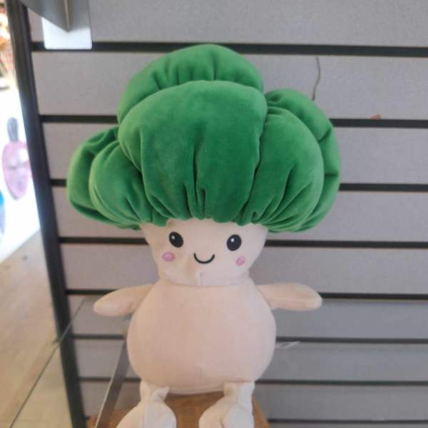 Plush toy with a large green top and cream body displayed on a shelf
