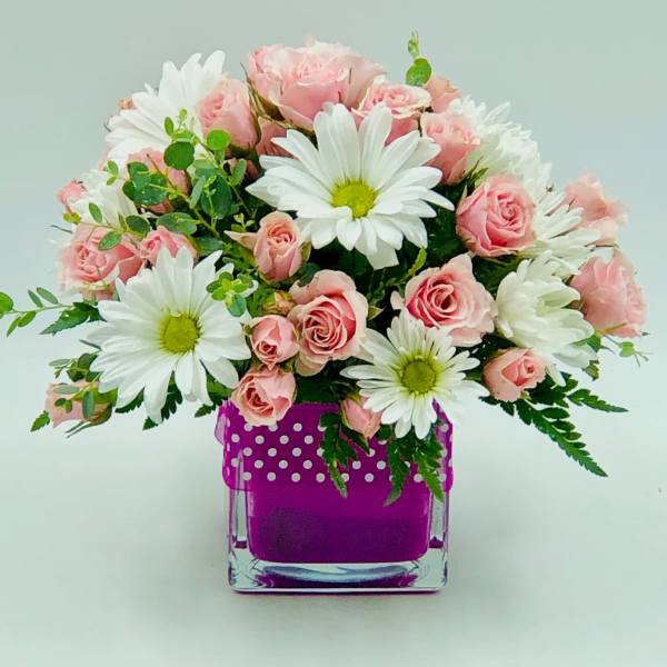 Pink roses and white daisies arranged in a purple glass vase