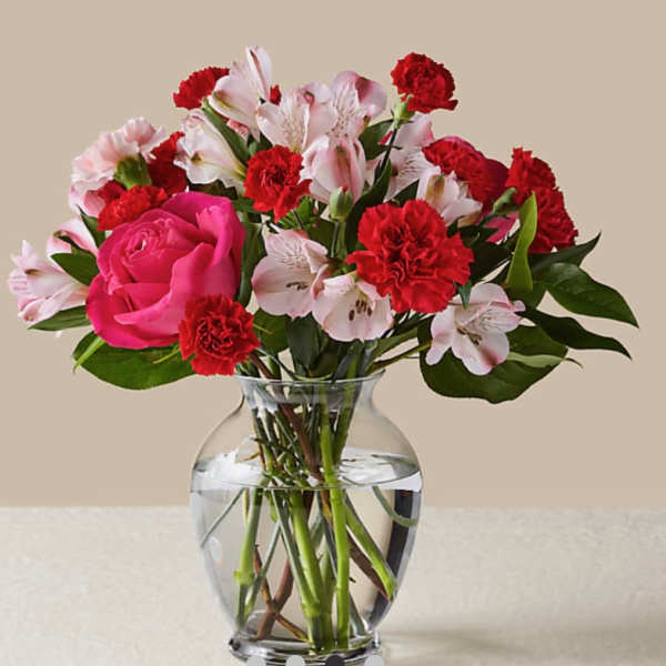 Pink rose and red carnation bouquet in a clear glass vase