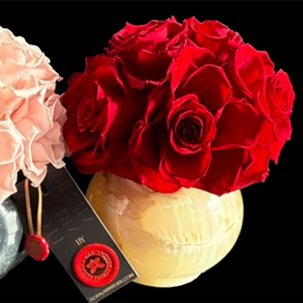 Two rose bouquets in round vases, one blush pink and one red