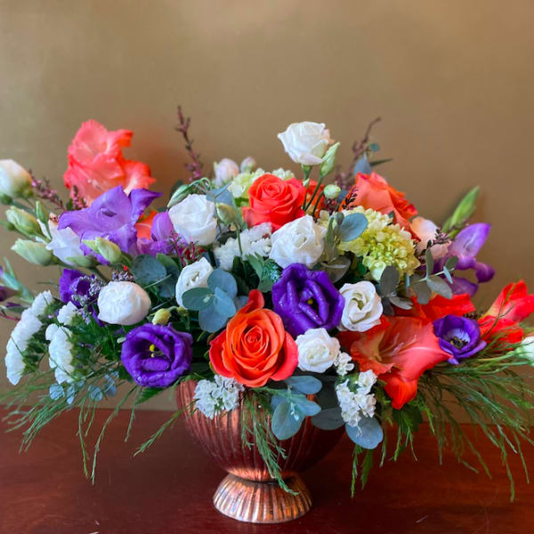 Mixed bouquet of roses and purple blooms in a copper vase