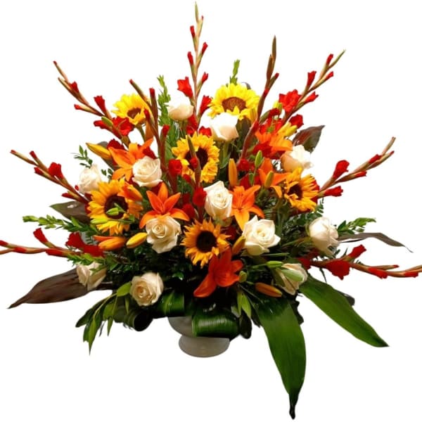 Large arrangement of sunflowers, orange lilies, and white roses in a low vase