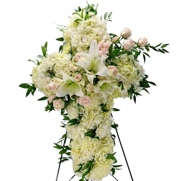 White floral cross arrangement with pale pink roses and lilies