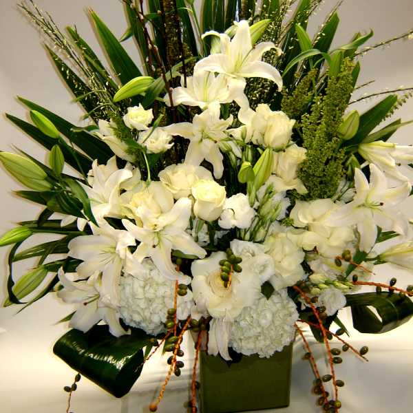 White lilies and roses arranged in a green square vase