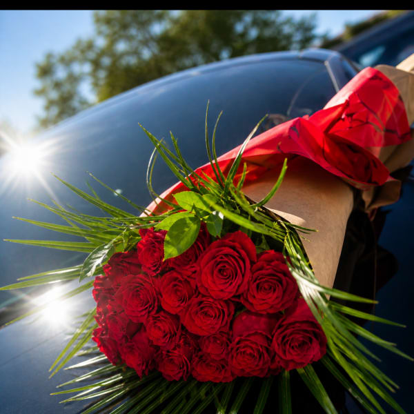Bouquet of red roses wrapped in brown paper with red ribbon