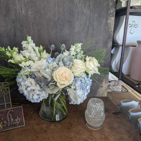 White and pale blue flower arrangement in a glass vase