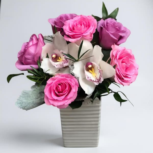 Pink roses and white orchids arranged in a ribbed vase