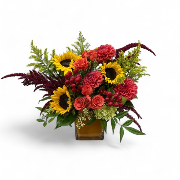 Mixed bouquet with sunflowers, coral roses, and red blooms in a glass vase