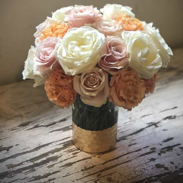 Bouquet of pale pink, white, and peach roses in a gold vase