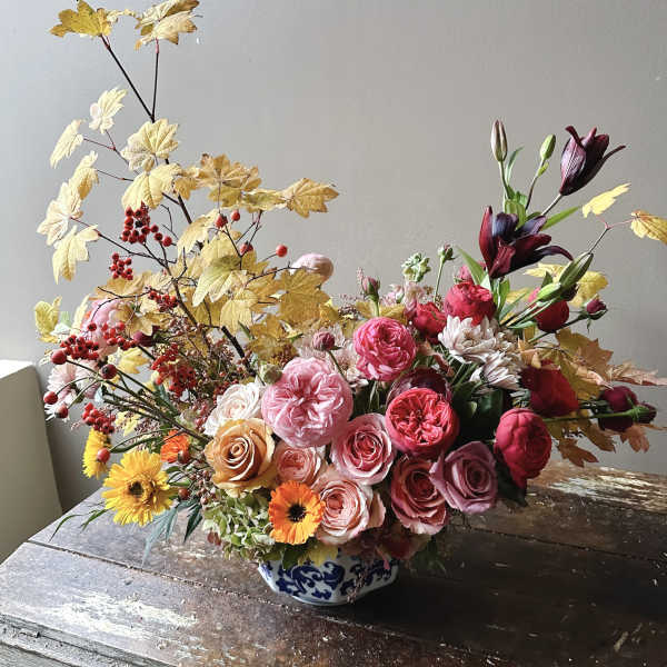 Mixed bouquet in a blue-and-white ceramic vase with roses and lilies