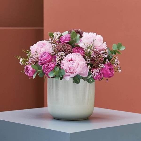 Pink floral arrangement in a ribbed white vase
