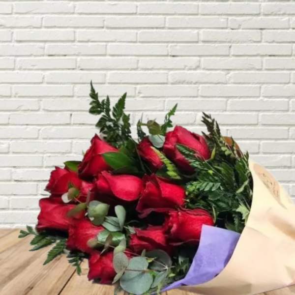 Bouquet of red roses wrapped in cream paper with a red ribbon