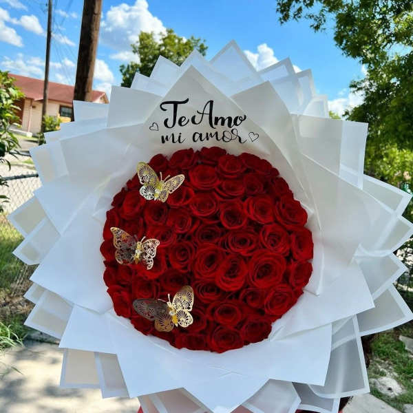 Large bouquet of red roses wrapped in white paper with butterfly accents