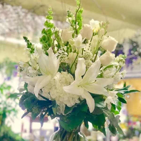 White lilies and roses arranged in a clear glass vase