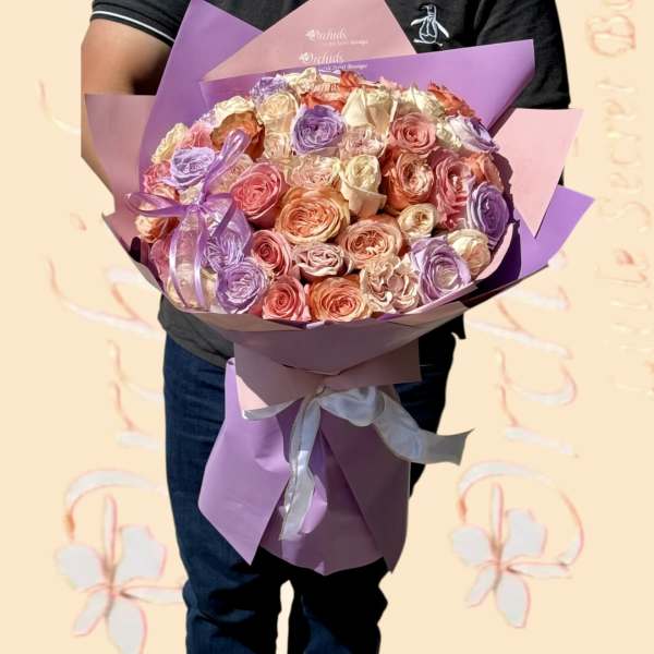Large bouquet of pastel roses wrapped in purple and pink paper