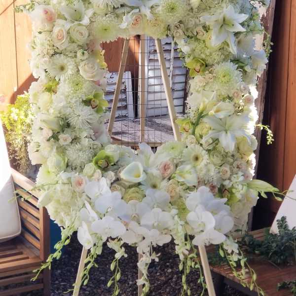 Large white floral wreath on a wooden easel