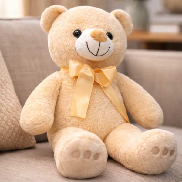 Plush teddy bear with a satin bow sitting on a sofa