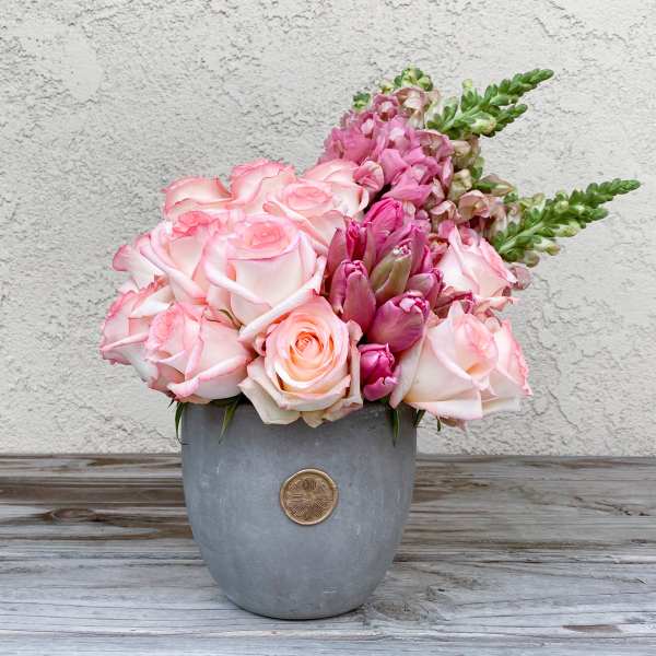 Pink roses and snapdragons arranged in a gray vase