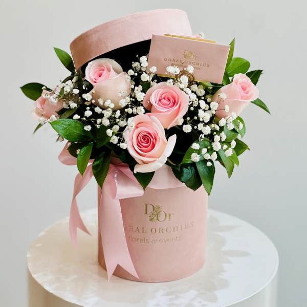 Pink roses with baby's breath in a pink hatbox with ribbon