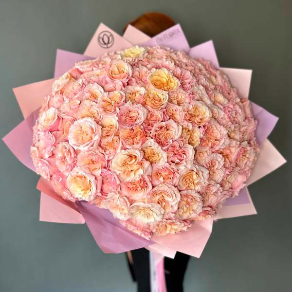 Large bouquet of pale pink and peach roses wrapped in pink paper
