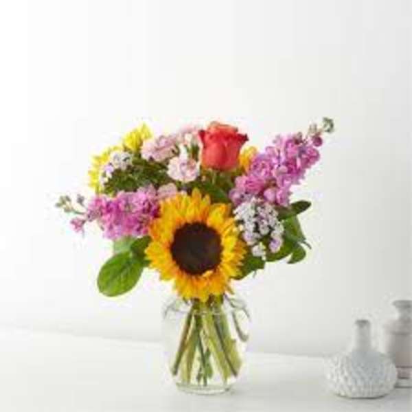 Bouquet with a sunflower, pink rose, and purple flowers in a glass vase