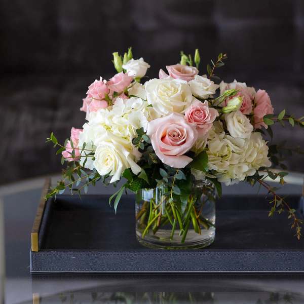 Pink and white roses arranged in a glass vase