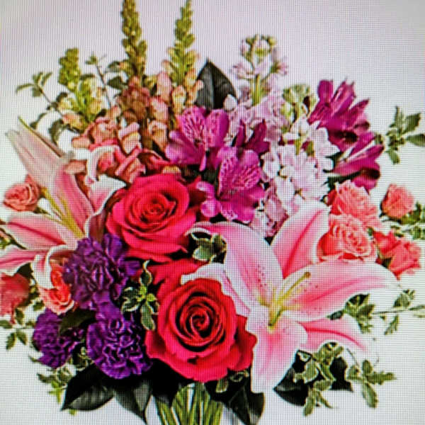 Mixed bouquet of pink lilies, roses, and purple flowers in a clear vase